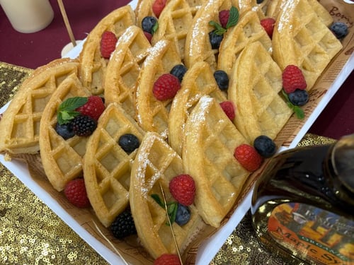 Platter of Belgian waffles with fresh berries and powdered sugar.