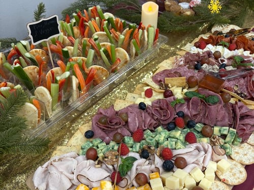 Large charcuterie board with meats, cheeses, crackers, and mini veggie cups.