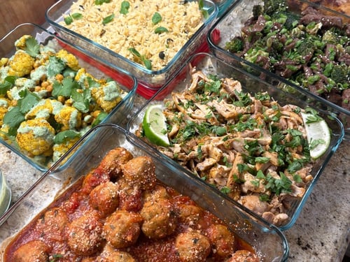 Assortment of globally-inspired meal prep dishes in glass containers.