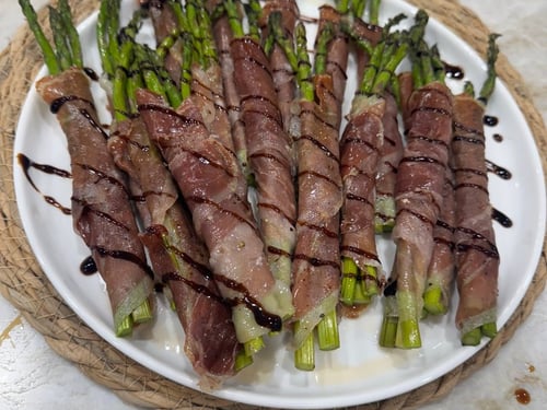 Prosciutto-wrapped asparagus spears drizzled with balsamic glaze.