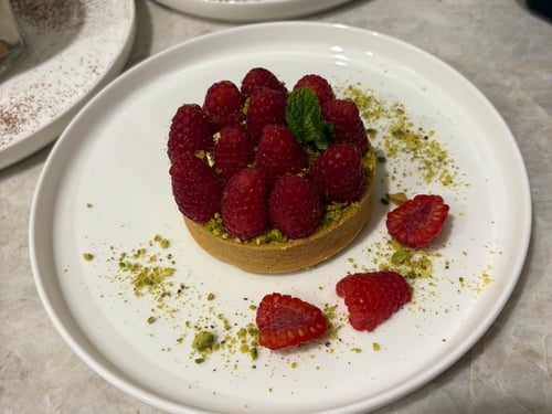 Raspberry tart with pistachios and a mint garnish.