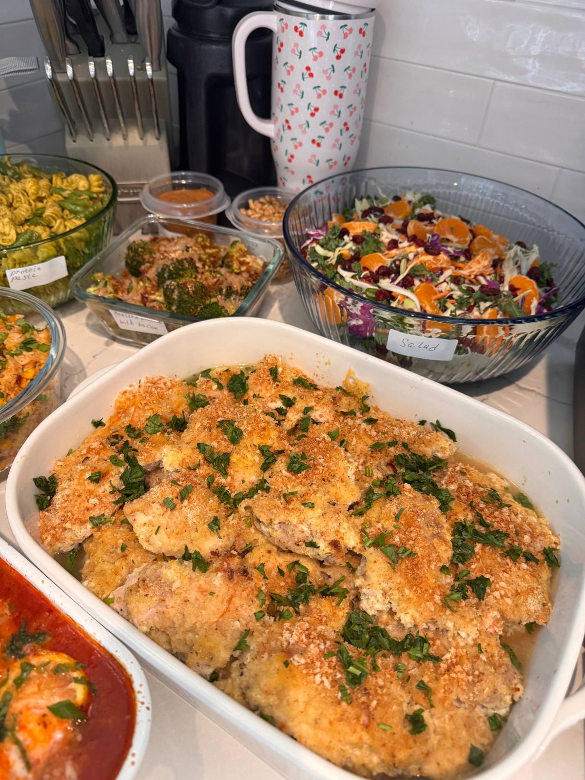 table filled with various dishes, including a large bowl of chicken