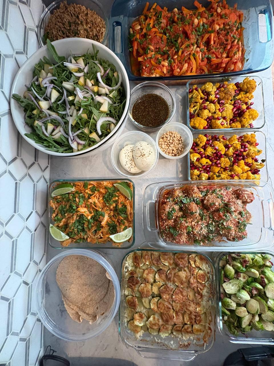 table filled with various dishes, including a bowl of salad