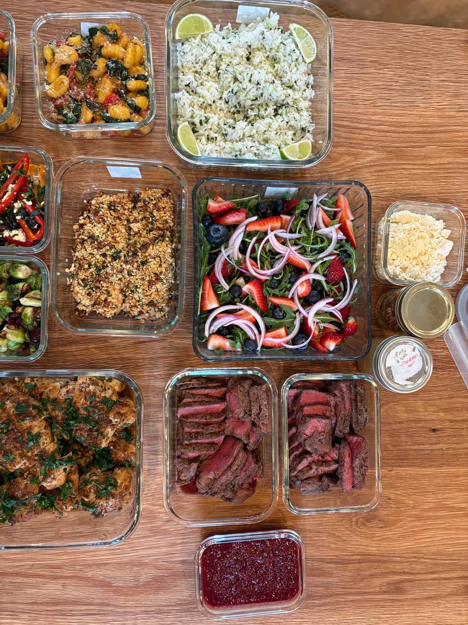 table filled with various foods, including meat, vegetables