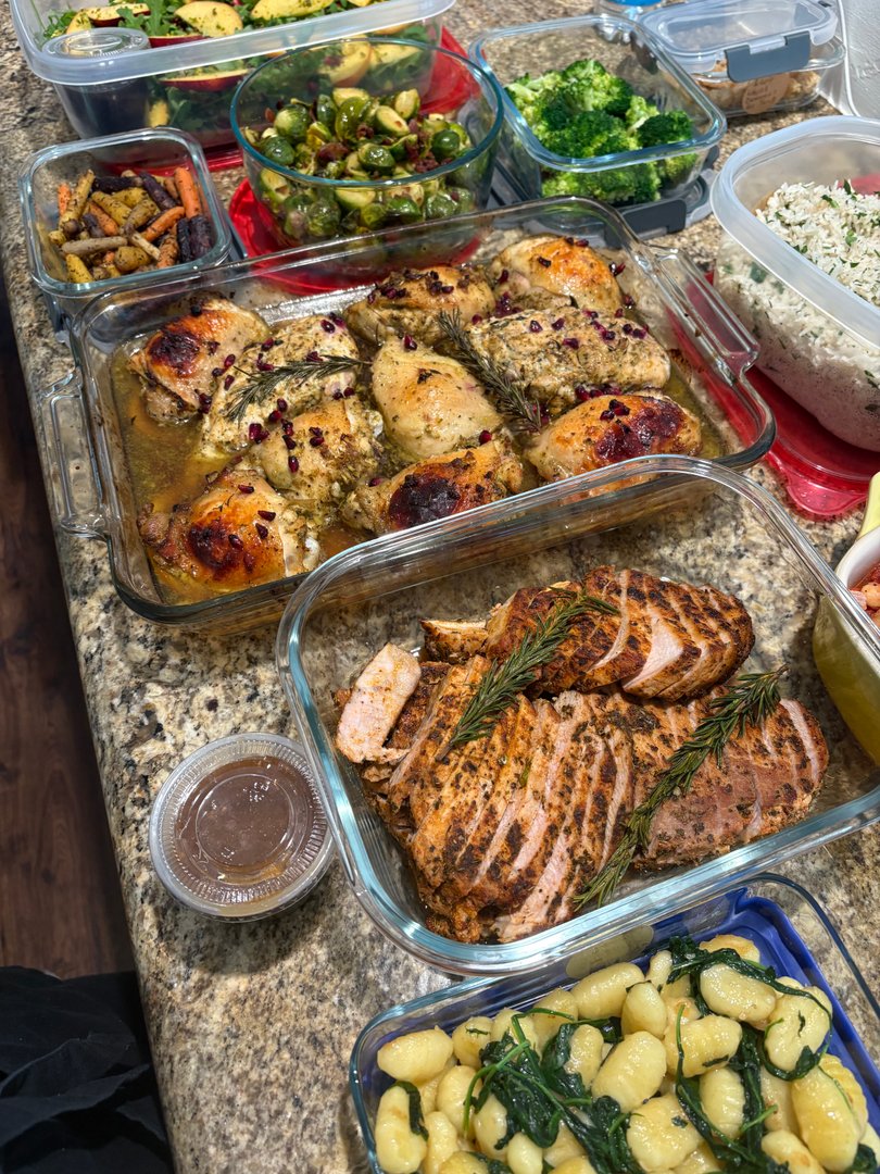 Gourmet meal prep with roasted chicken, sliced pork, gnocchi, and vegetables.