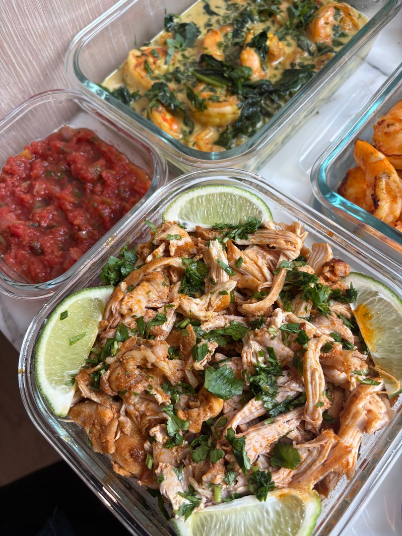 Close-up of shredded chicken with lime wedges and salsa.