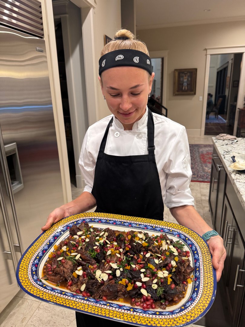 Chef Ana proudly holding the platter of slow-cooked lamb shoulder.