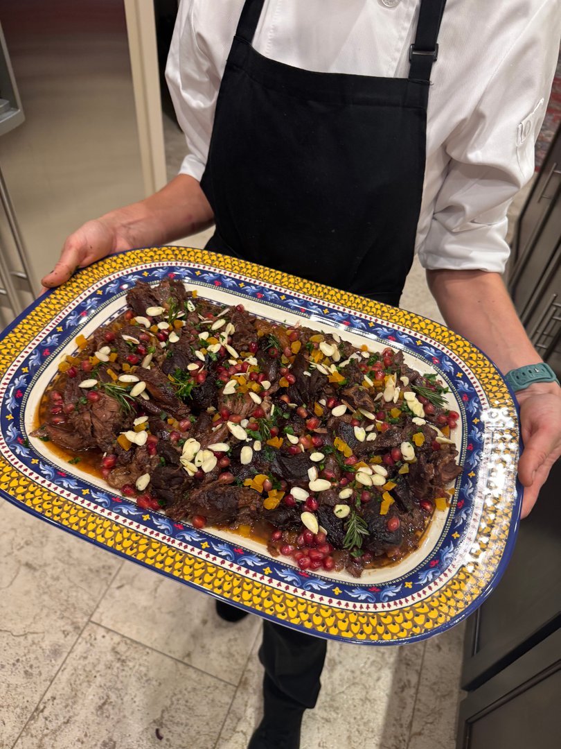 Close-up of Chef Ana holding the slow-cooked lamb shoulder platter.