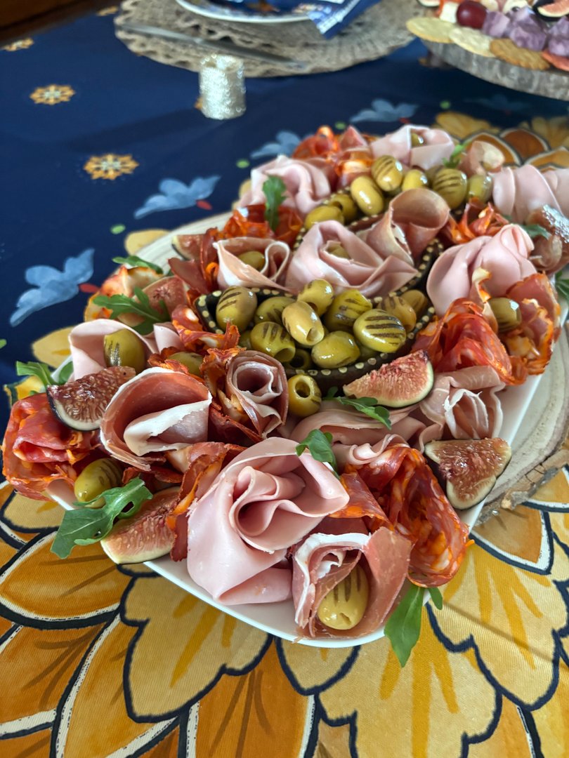 Elegant charcuterie board with olives, folded meats, and figs.