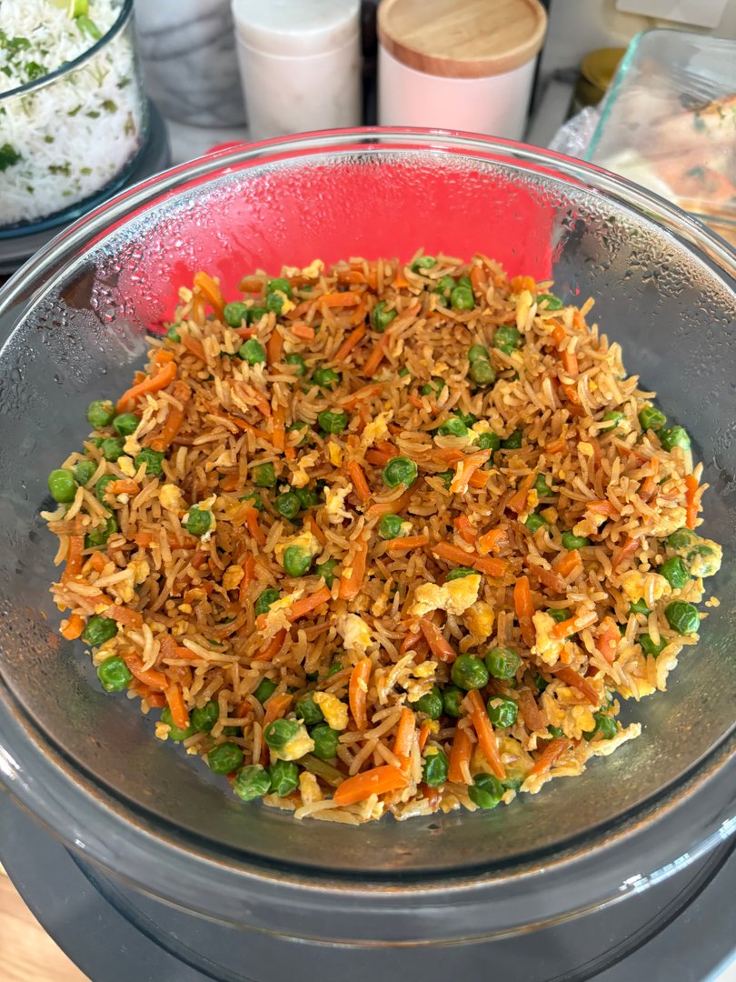 Fried rice with peas, carrots, and scrambled egg in a glass bowl.