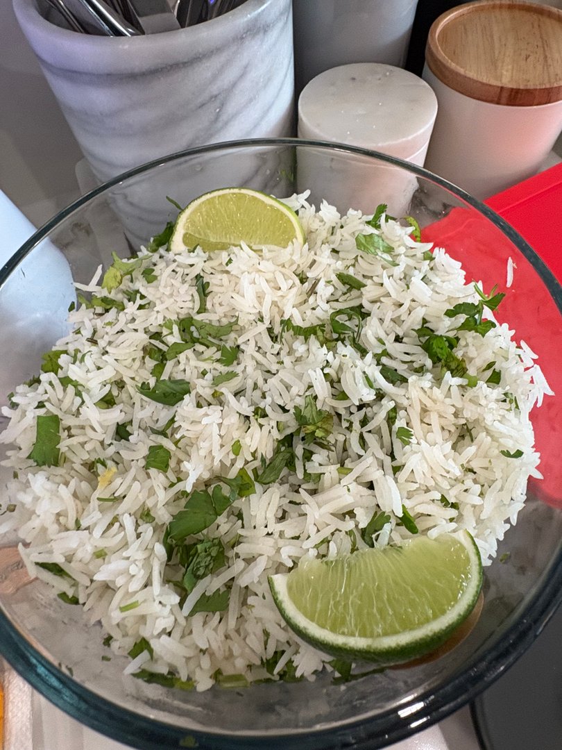 Cilantro lime rice with fresh lime wedges in a clear bowl.