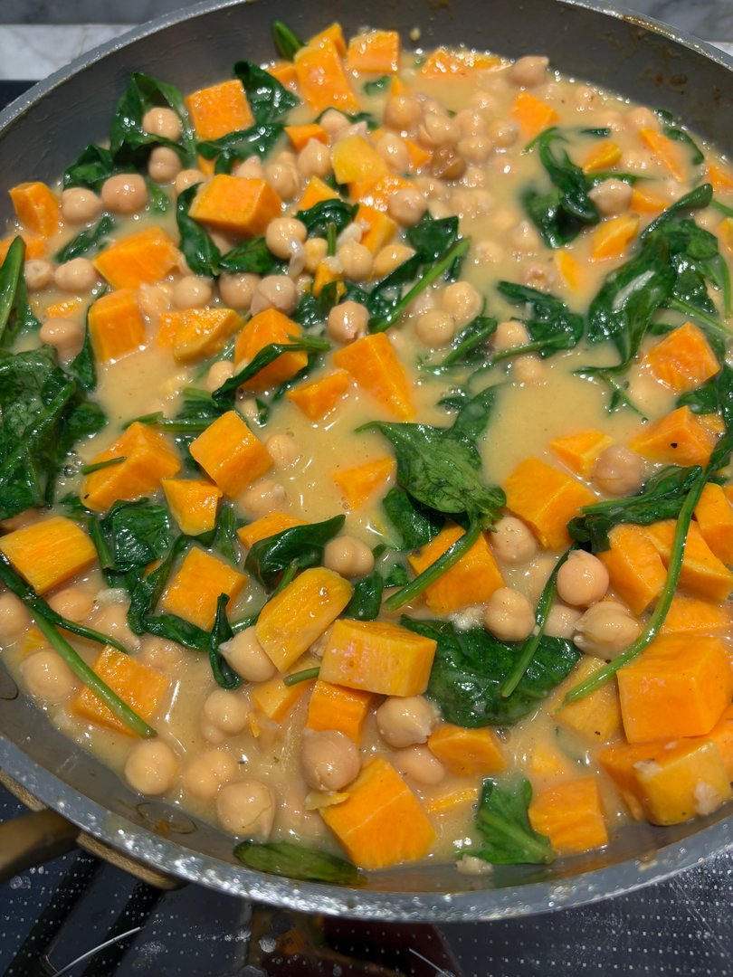 Close-up of sweet potato, chickpea, and spinach curry in a pan.