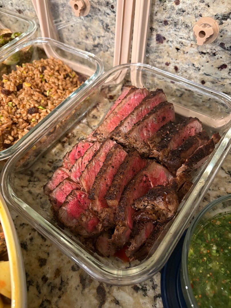 Close-up of perfectly sliced, medium-rare steak in a glass container.