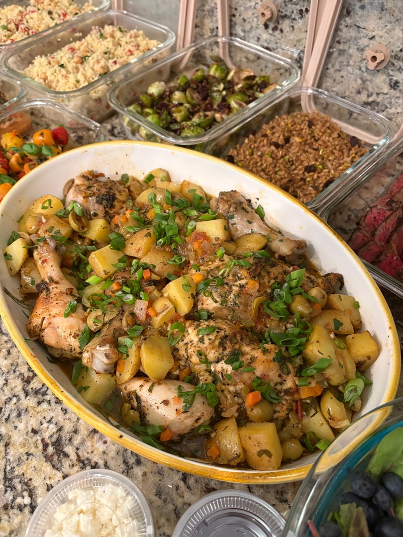 Large oval dish of roasted chicken and potatoes with herbs.