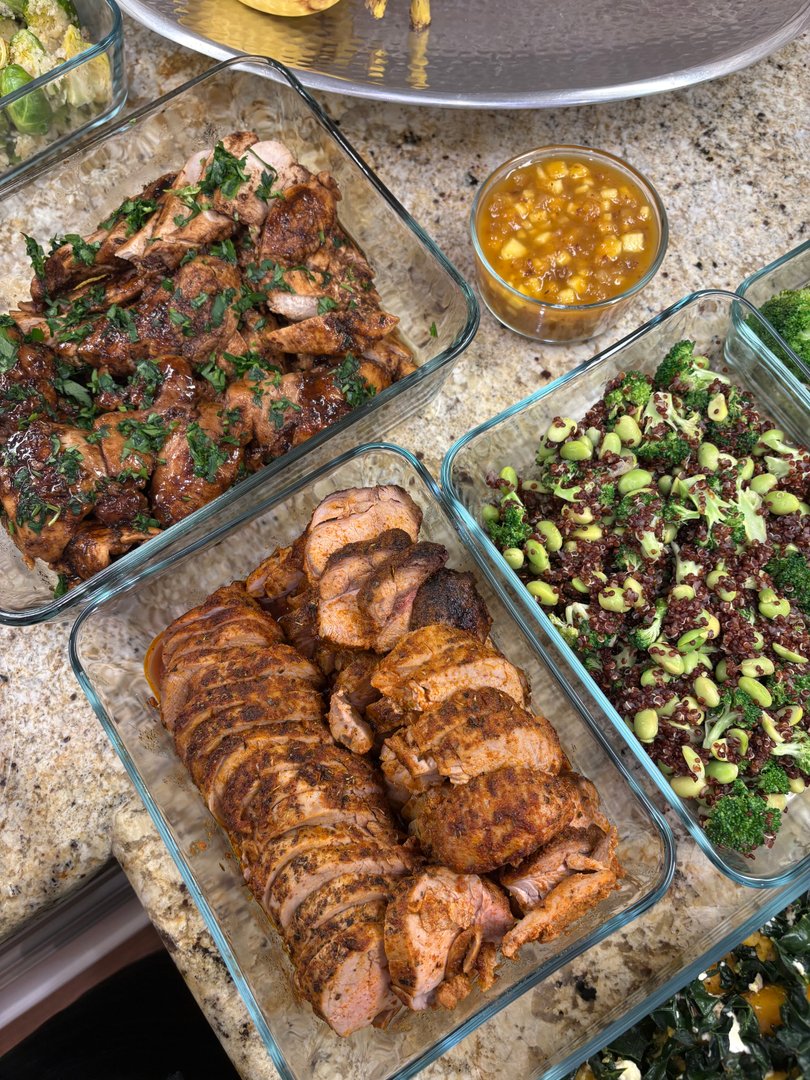 Prepared chicken, pork tenderloin, and quinoa salad in glass containers.