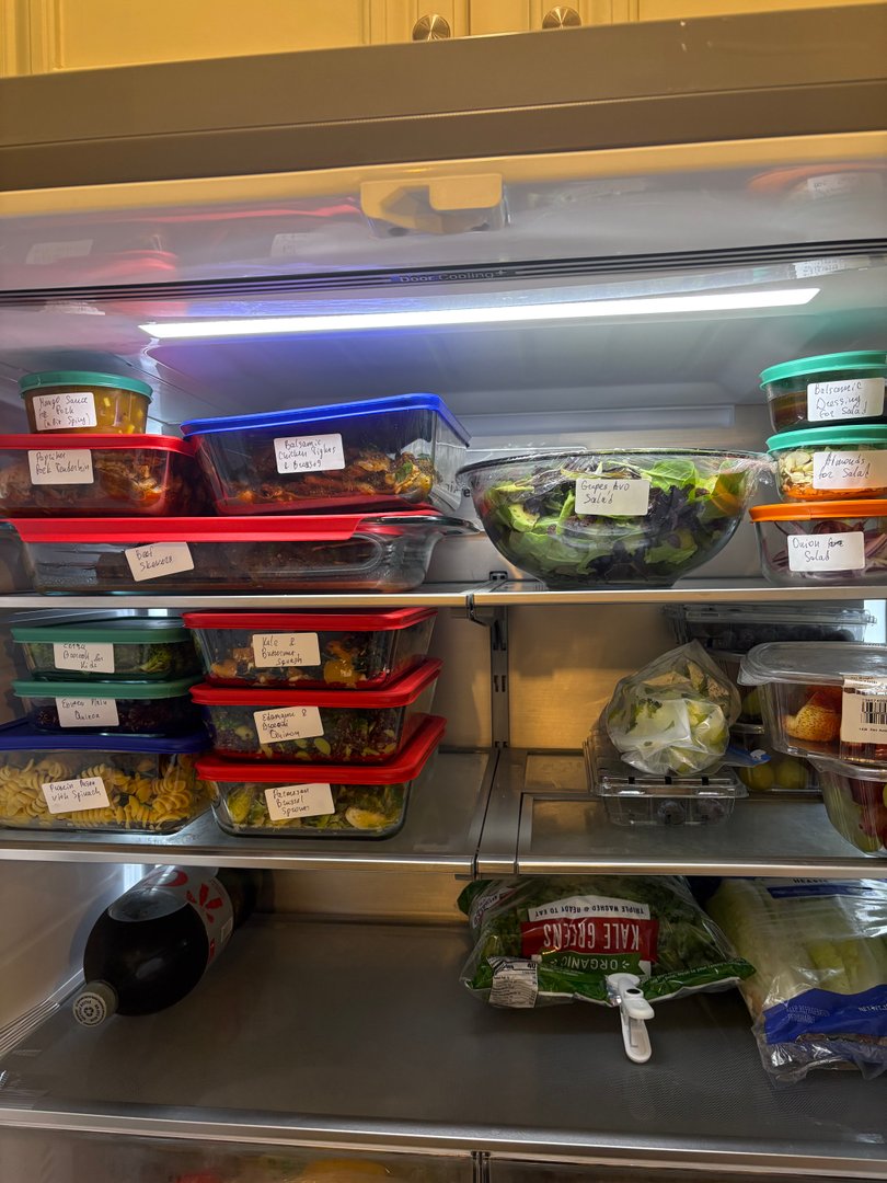 Refrigerator filled with neatly organized meal prep containers and fresh produce.