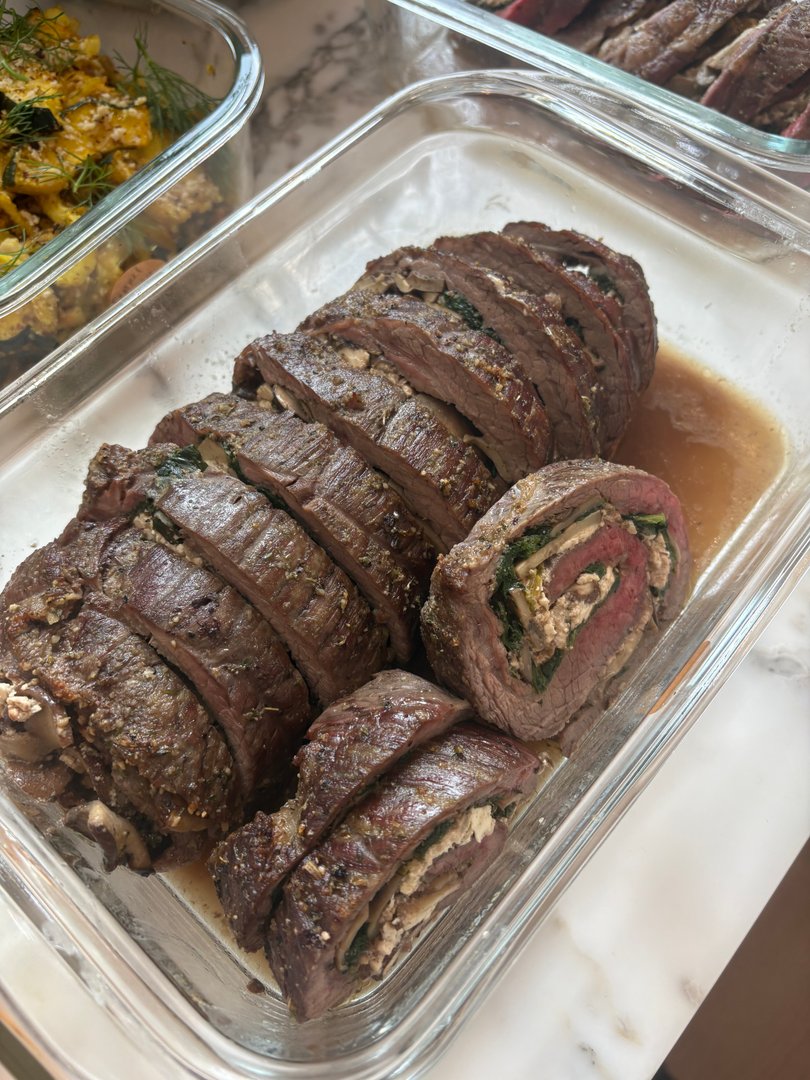 Sliced beef roulade with savory filling in a glass dish.
