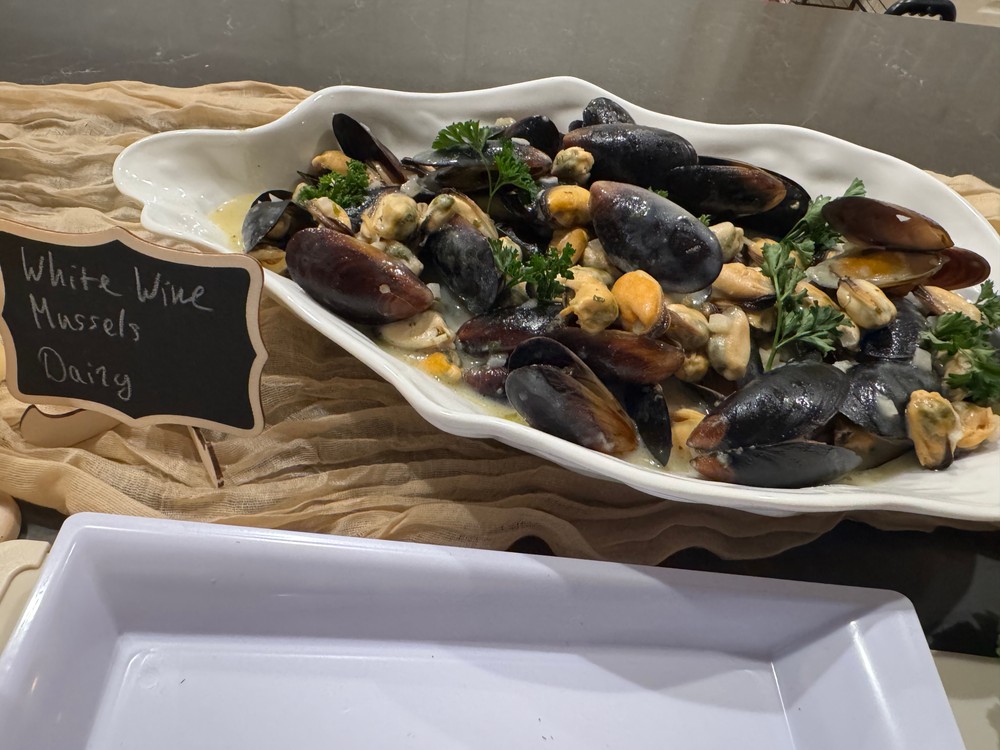 Mussels in creamy wine sauce with parsley garnish in a white serving dish