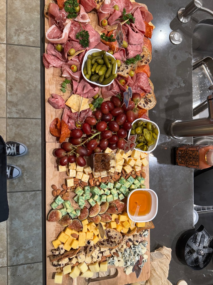 Overhead view of meat and cheese charcuterie boards with fruits, nuts, honey