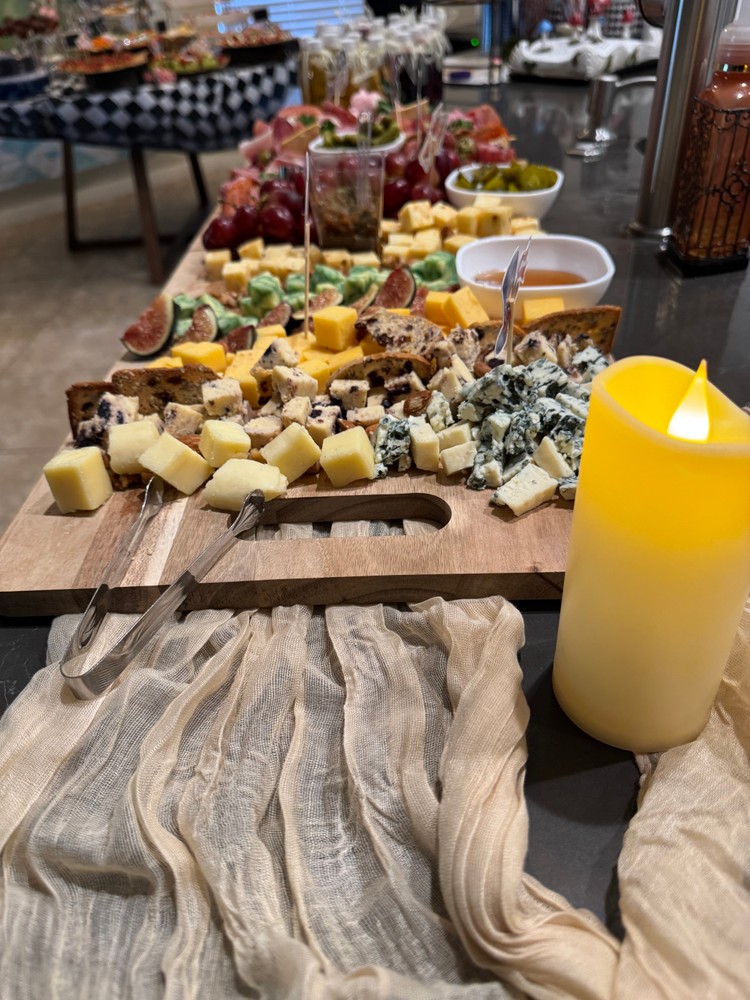 Cheese charcuterie board with various cheeses, figs, grapes, and honey