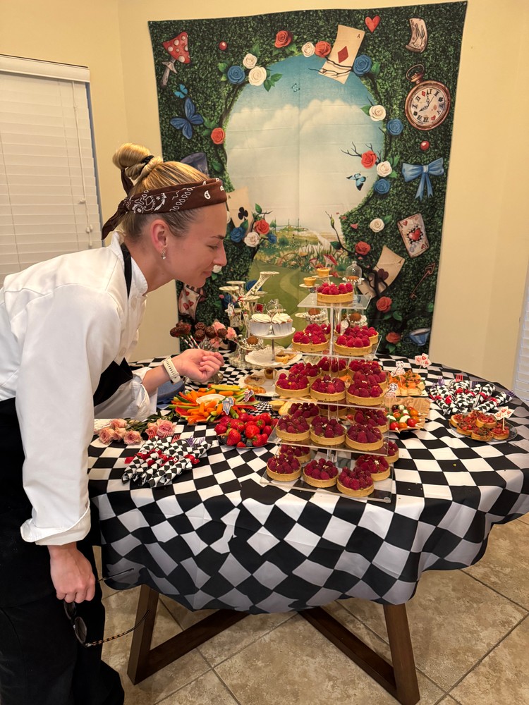 Chef Ana setting up dessert table with raspberry tarts and other treats