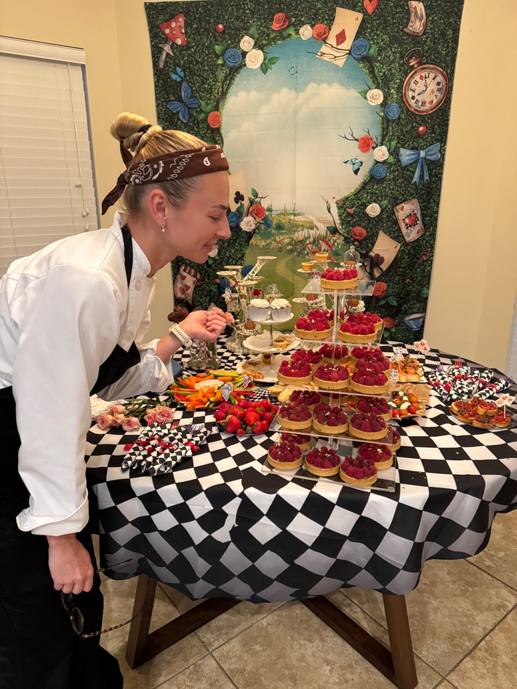 Chef Ana smiling while arranging a dessert table with various sweets
