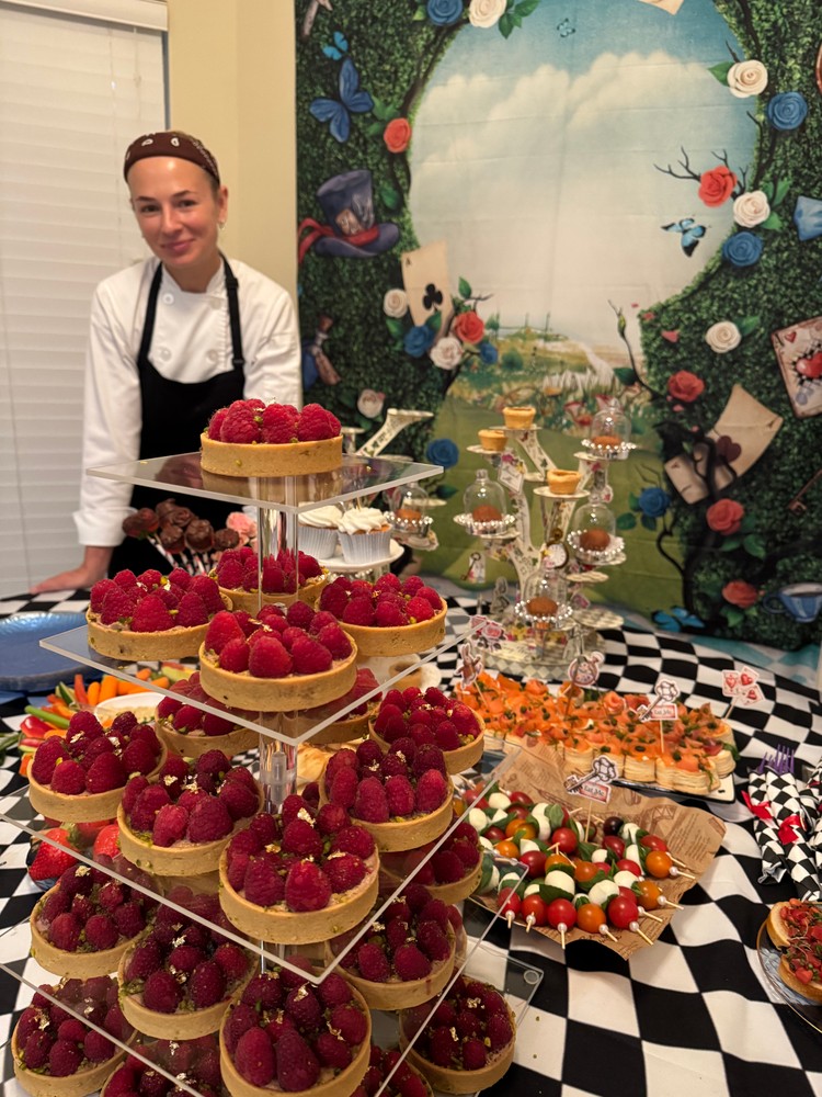 Chef Ana presenting a buffet with raspberry tarts and appetizers