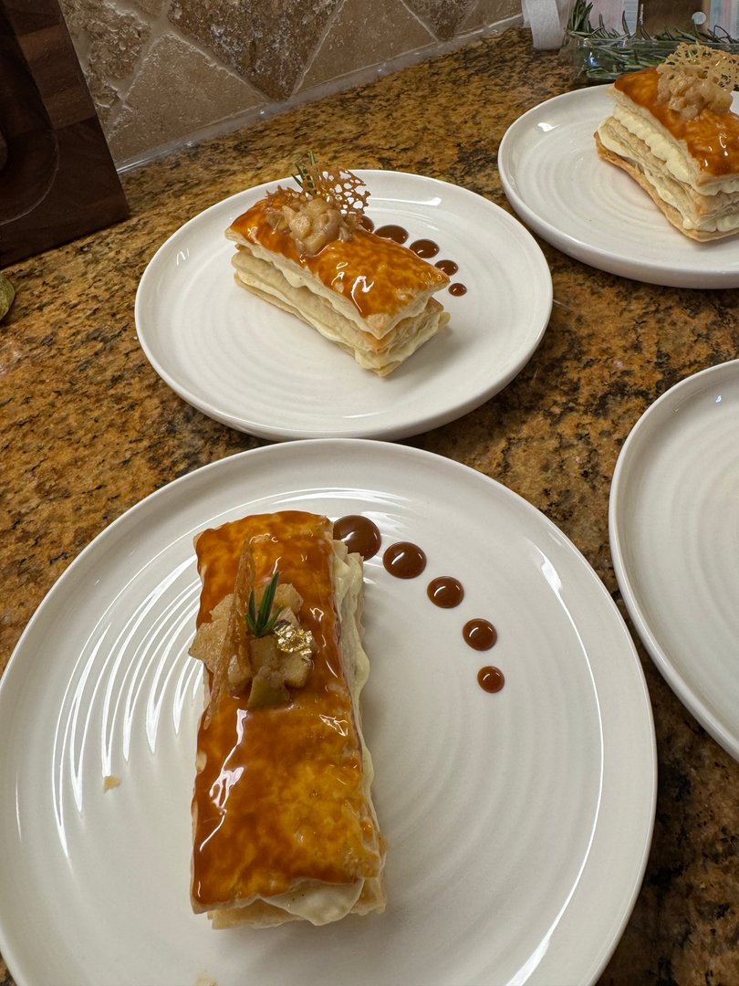 Plated Mille-Feuille dessert with caramel glaze and delicate crispy garnish.